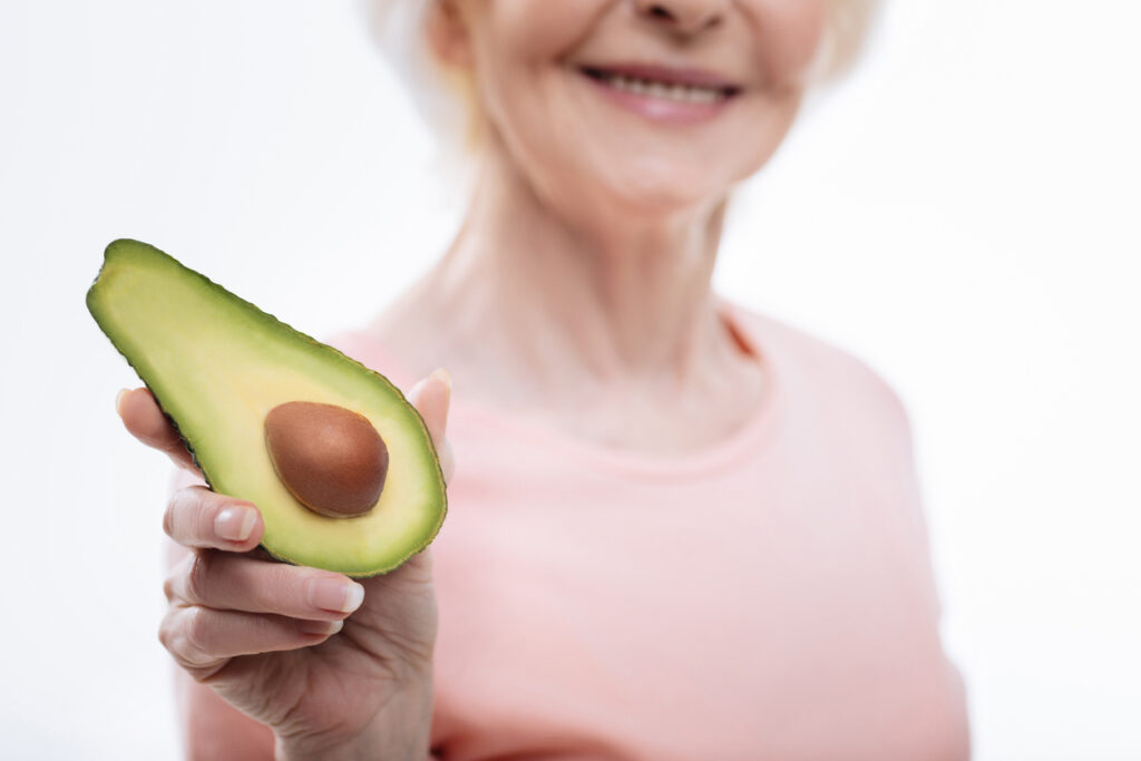 Senior woman holding half an avocado. Foods to help arthritis