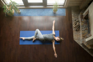 young woman doing a side stretch on yoga mat