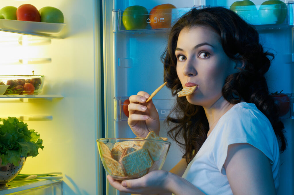 Woman eating from fridge. Foods to avoid
