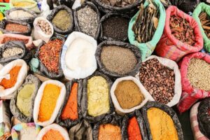 A variety of herbs, spices, beans and cocoa in bags on a table.
