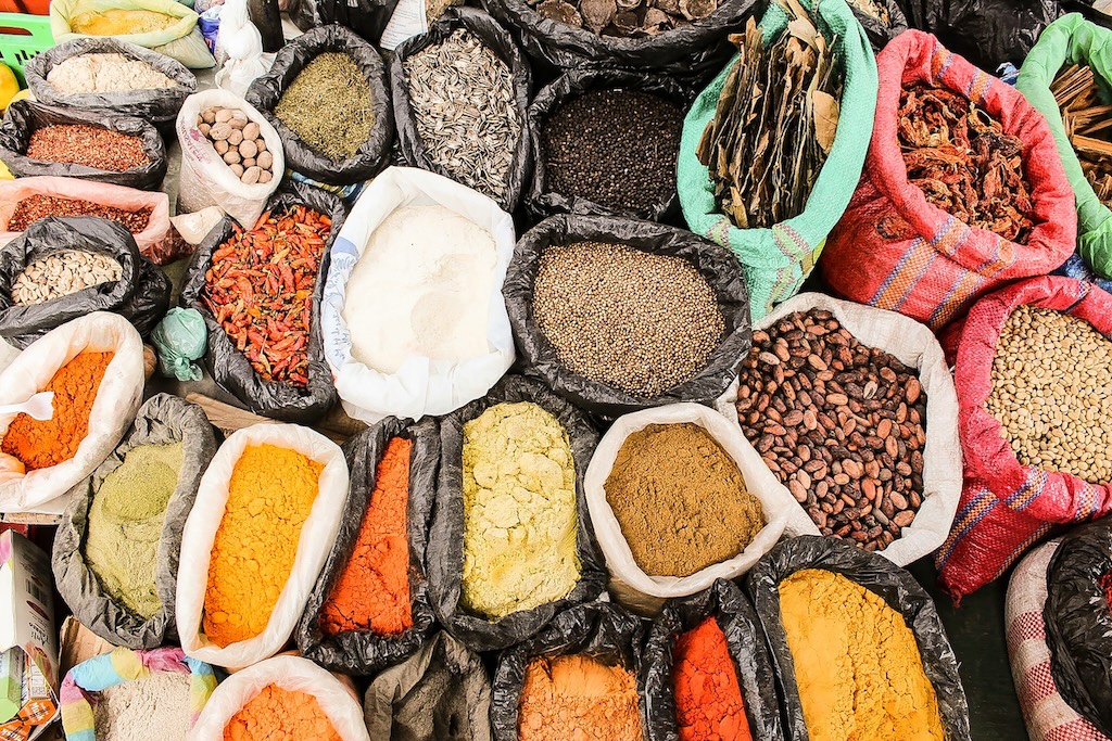 A variety of herbs, spices, beans and cocoa in bags on a table.